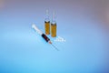 On a blue background, a syringe and two bottles of injections Royalty Free Stock Photo